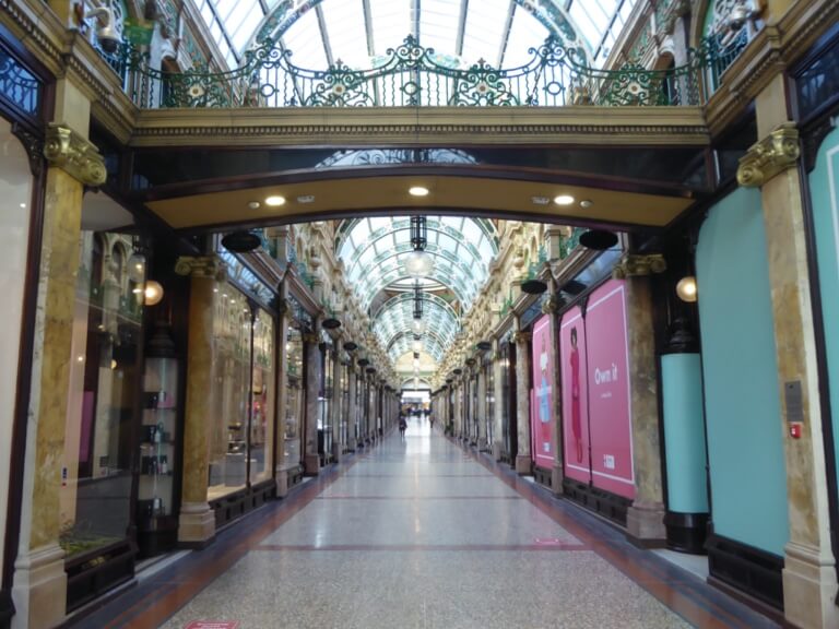 One of the Victoria Quarter shopping streets, with marble columns and a glass roof.
